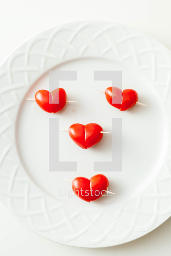Heart shaped tomato h'or d'oeuvres on a white plate.