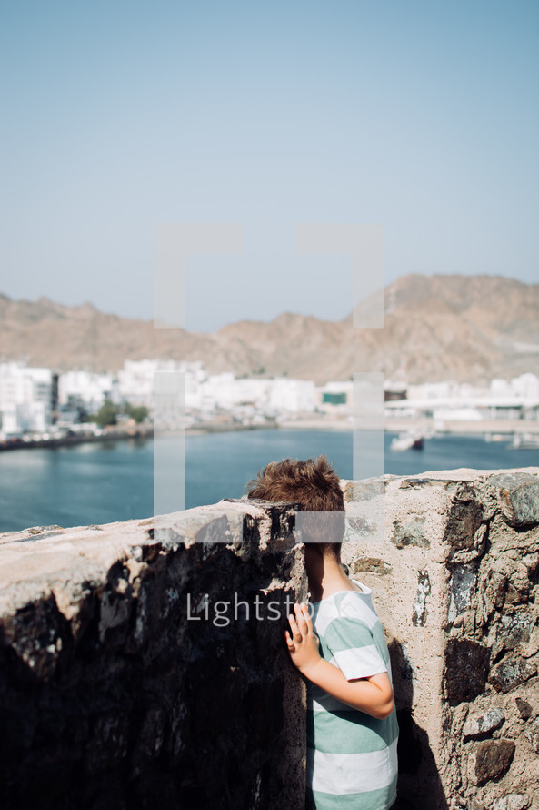 Little boy looking at the scenic view from the Muttrah Fort in Muscat, Oman