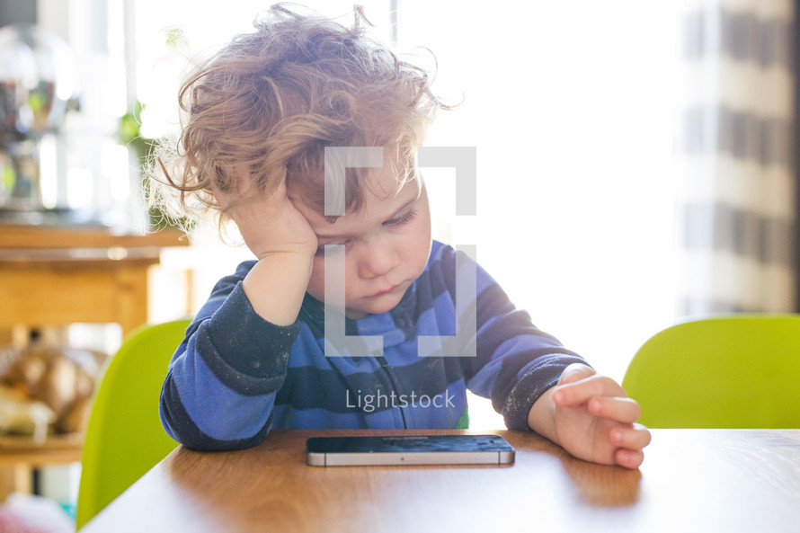 a toddler boy playing on a cellphone 