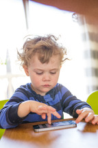 a toddler boy playing on a cellphone 