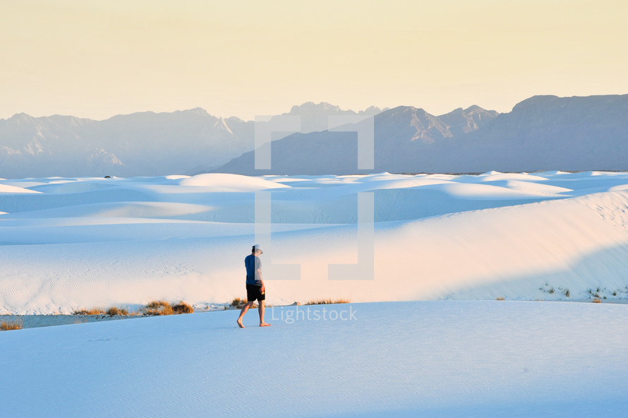 a man walking on sand dunes 
