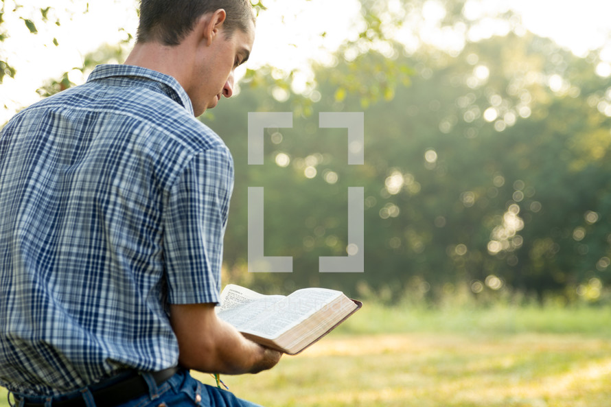 a man reading a Bible outdoors 