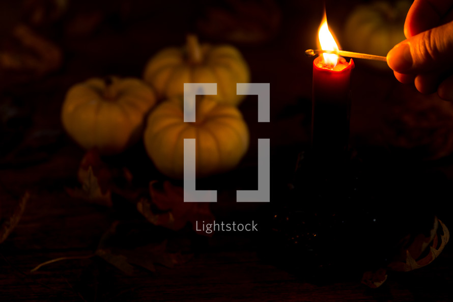 lighting a candle with pumpkins