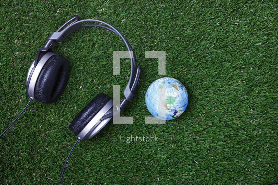 headphones and globe on grass