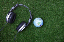 headphones and globe on grass