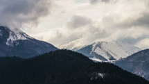 Time lapse of clouds moving over alpine mountains in winter. 
