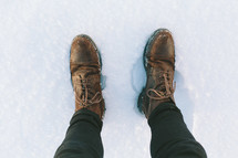 Feet in boots standing in snow.