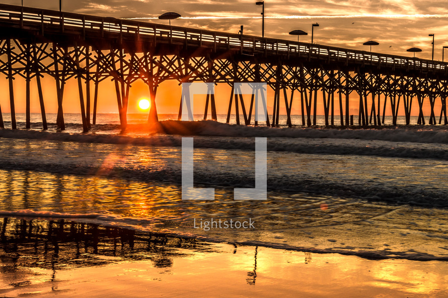 sun setting near a beach pier 