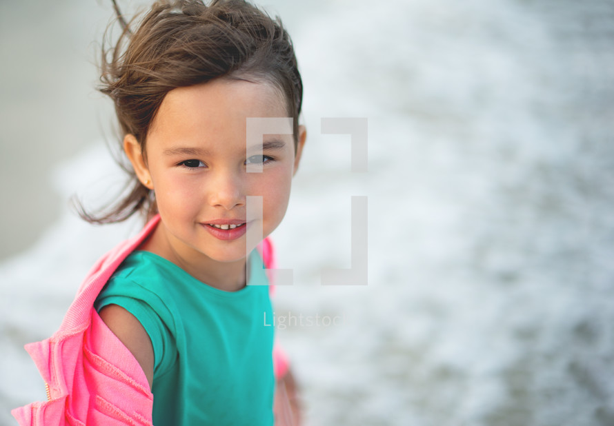 Portrait of little girl smilling and having fun in the sea waves