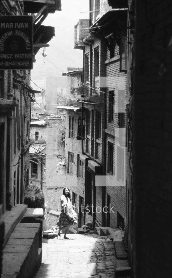 a woman walking in a narrow alley 