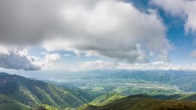 Panoramic view of green alpine mountains landscape with clouds moving fast in sunny spring Time-lapse
