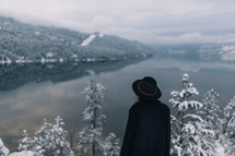 a woman standing on the edge of a snowy mountainside 