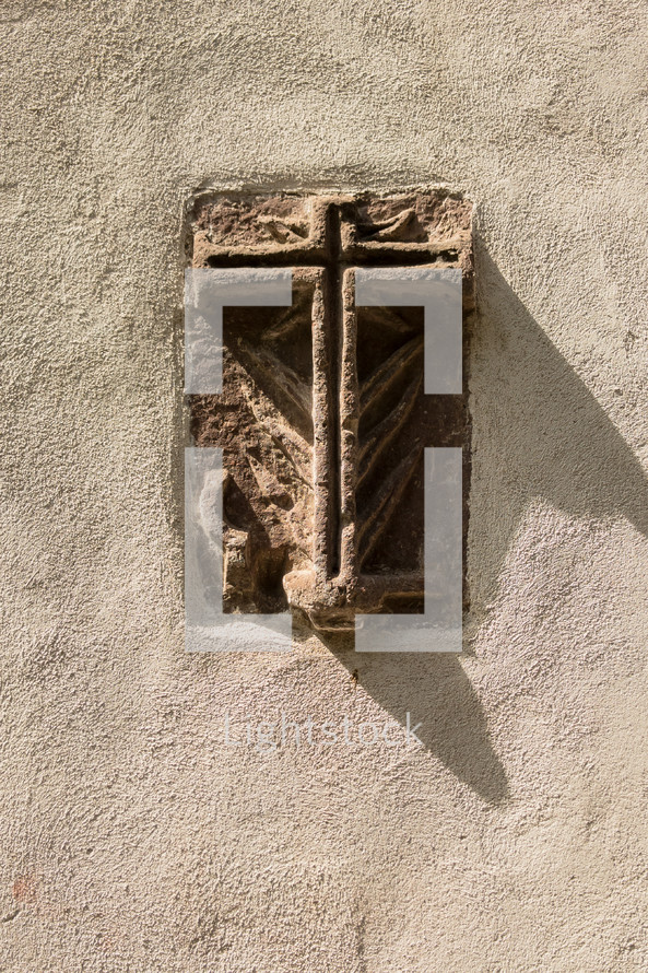 stone cross engraved in the side of a wall 