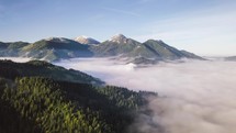 Aerial view of alpine mountains over misty forest nature in cold autumn morning Hyper lapse
