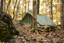 a green military tent in the woods