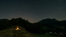A bunch of friends sitting around campfire in starry night sky in summer nature Time-lapse
