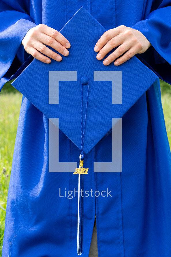 female graduate outdoors holding a graduation cap 