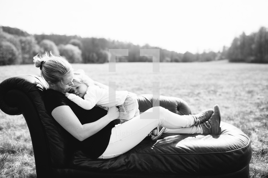 Mother and child on a couch in a field of grass.