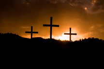 sun setting behind three crosses