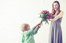 Boy giving bouquet of flowers to his mother.