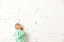 little boy facing a wall