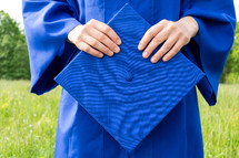  female graduate outdoors holding her cap 
