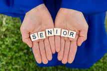 word senior in cupped hands of a graduate 