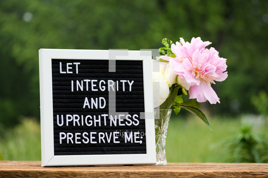 a sign board with bible verse and flowers