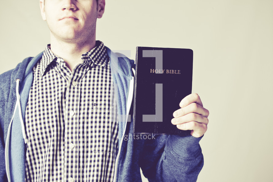 man holding up a Holy Bible