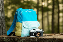 a backpack and retro camera on a bench in the woods
