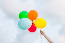 a bunch of colorful balloons with cloudy skies