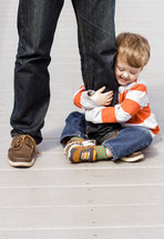 toddler hugging father's leg 