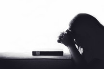 Silhouette woman praying on holy bible in the morning