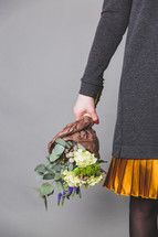 a woman holding a bouquet of flowers by her side 