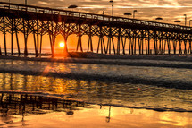 sun setting near a beach pier 