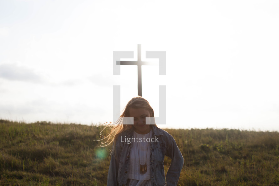 a woman praying in front of a cross