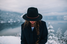 a woman in a hat standing on a snowy mountain top looking down 