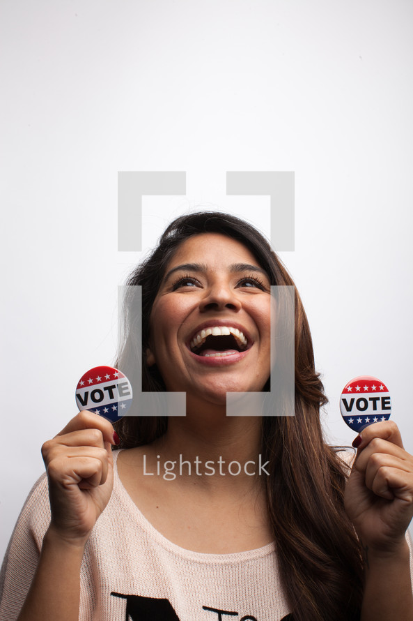 young woman holding vote buttons 