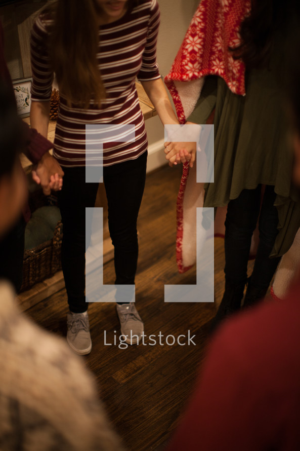 teens holding hands in prayer at a Christmas party 
