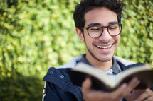 a smiling man reading a Bible 