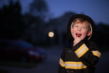 a boy in a fire fighter Halloween costume eating candy 