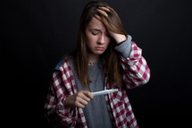 a teen girl holding a pregnancy test 