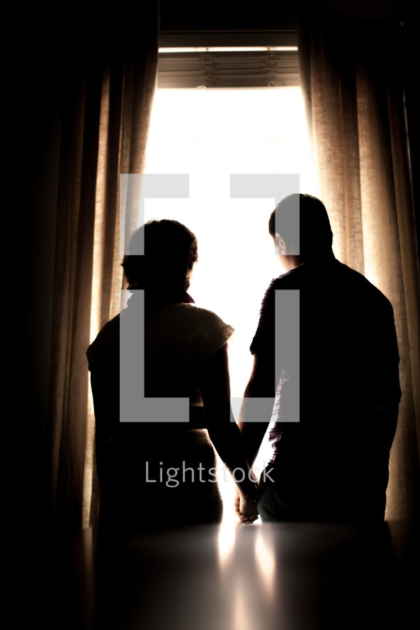 silhouette of a couple standing in a window 