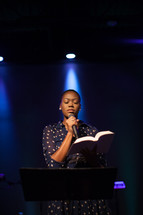 A woman on stage leading a worship service 