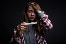 teen girl looking at a pregnancy test 