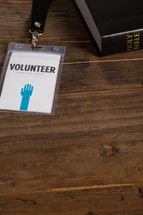 A volunteer badge on a table next to a Bible.