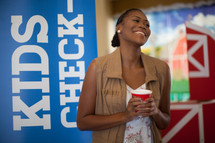 A woman standing in front of a kids check in sign 
