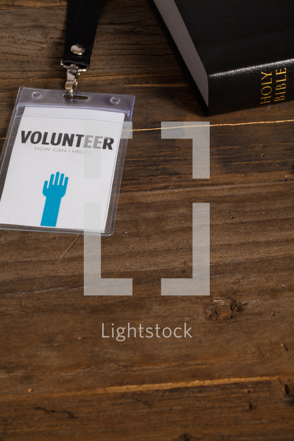 A volunteer badge on a table next to a Bible.