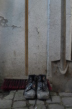 old worn painted work boots with a yard broom and a spade