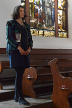 a woman walking into an empty church with her Bible 